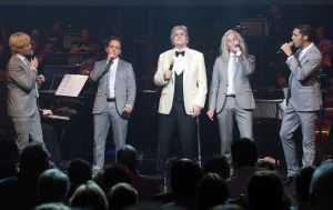 26-04-2013 SHOWBIZZ; GORDON NU OOK PROBLEMEN MET ZIJN VOICES. Gordon is van mening dat hij geen absurde eisen stelt aan zijn ex-collega s van LA The Voices. Ik heb de naam verzonnen, ik heb alles opgebouwd.
Donderdagavond werd bekend dat Gorden en de overige vier zangers van de groep behoorlijke ruzie over geld hebben sinds Gordon besloten heeft ermee te stoppen. Ze hebben zelfs advocaten in de arm genomen om het uit te vechten. Die jongens moeten gewoon een bedrag betalen per optreden of per gekochte cd, vindt Gordon. Dat is volkomen normaal.

De andere Voices zijn het hier volledig mee oneens. Hij kan niet vanuit Blaricum met een afstandsbediening het schip blijven besturen, zegt Peter Strykes, een van hen. Ik dacht dat de slavernij al heel lang geleden was afgeschaft. Toch hoopt Strykes dat ze er nog zonder advocaat uit kunnen komen. Ik houd niet van moddergooien.
Afgelopen week had Gordon ook al een hevige ruzie met Mark v.d.Linden.
The Voices waren 3 dagen te gast in de theater show van Lee Towers in het Nieuwe Luxor te Rotterdam, wat een daverend succes was.
foto: Albert den Iseger.