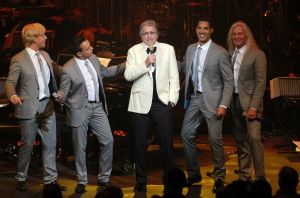 26-04-2013 SHOWBIZZ; GORDON NU OOK PROBLEMEN MET ZIJN VOICES. Gordon is van mening dat hij geen absurde eisen stelt aan zijn ex-collega s van LA The Voices. Ik heb de naam verzonnen, ik heb alles opgebouwd.
Donderdagavond werd bekend dat Gorden en de overige vier zangers van de groep behoorlijke ruzie over geld hebben sinds Gordon besloten heeft ermee te stoppen. Ze hebben zelfs advocaten in de arm genomen om het uit te vechten. Die jongens moeten gewoon een bedrag betalen per optreden of per gekochte cd, vindt Gordon. Dat is volkomen normaal.

De andere Voices zijn het hier volledig mee oneens. Hij kan niet vanuit Blaricum met een afstandsbediening het schip blijven besturen, zegt Peter Strykes, een van hen. Ik dacht dat de slavernij al heel lang geleden was afgeschaft. Toch hoopt Strykes dat ze er nog zonder advocaat uit kunnen komen. Ik houd niet van moddergooien.
Afgelopen week had Gordon ook al een hevige ruzie met Mark v.d.Linden.
The Voices waren 3 dagen te gast in de theater show van Lee Towers in het Nieuwe Luxor te Rotterdam, wat een daverend succes was.
foto: Albert den Iseger.