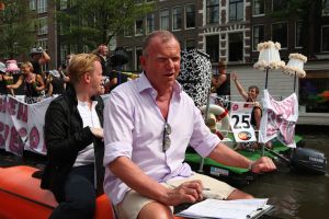 06-08-2009 SHOWBIZZ; GAY PRIDE AMSTERDAM TREKT MEER DAN 600.000 BEZOEKERS. Een giga festijn de 2009 Gay Pride in Amsterdam, duizenden bootjes, honderdduizenden bezoekers en een Sinterklaas die na het uur moest worden opgenomen met wel heel vreemde verschijnselen, en als wij de media moeten geloven na het drinken van een wodkaatje. Wij weten beter want wij waren er smorgens vroeg al bij,plaats van alle verrassingen De Westerdok haven.Toen was het nog niet heet, er waaide een heerlijk windje en de aanwezige BNers hadden er zin in, zelfs Sint Nicolaas of te wel Gordon. Menig drankje gleed naar binnen voordat de boten vertrokken richting de Prinsengracht. Als dat maar goed gaat dacht ik nog. En het ging niet goed, Sint Nicolaas werd witter dan wit en werd lieftallig verzorgd door de dames met ijsklontjes. Niks hitte beroerte of een schommelende boot, zware mijter of Sinterklaaspak van velours. Gordon droeg een wit katoenen pantalon en een katoenen hemt met inderdaad een mantel die helemaal los hing. Niks bevangen door de hitte, andere oorzaken dwongen hem tot stoppen van de Stoompoot boot. Sinterklaas werd afgevoerd in een ambulance voor verder onderzoek. Zondag avond was Gordon weer van de partij om de Gay Pride party te besluiten met een optreden. Al met al weer een zeer bewogen weekend voor vele mensen.
foto: Albert den Iseger