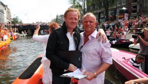 06-08-2009 SHOWBIZZ; GAY PRIDE AMSTERDAM TREKT MEER DAN 600.000 BEZOEKERS. Een giga festijn de 2009 Gay Pride in Amsterdam, duizenden bootjes, honderdduizenden bezoekers en een Sinterklaas die na het uur moest worden opgenomen met wel heel vreemde verschijnselen, en als wij de media moeten geloven na het drinken van een wodkaatje. Wij weten beter want wij waren er smorgens vroeg al bij,plaats van alle verrassingen De Westerdok haven.Toen was het nog niet heet, er waaide een heerlijk windje en de aanwezige BNers hadden er zin in, zelfs Sint Nicolaas of te wel Gordon. Menig drankje gleed naar binnen voordat de boten vertrokken richting de Prinsengracht. Als dat maar goed gaat dacht ik nog. En het ging niet goed, Sint Nicolaas werd witter dan wit en werd lieftallig verzorgd door de dames met ijsklontjes. Niks hitte beroerte of een schommelende boot, zware mijter of Sinterklaaspak van velours. Gordon droeg een wit katoenen pantalon en een katoenen hemt met inderdaad een mantel die helemaal los hing. Niks bevangen door de hitte, andere oorzaken dwongen hem tot stoppen van de Stoompoot boot. Sinterklaas werd afgevoerd in een ambulance voor verder onderzoek. Zondag avond was Gordon weer van de partij om de Gay Pride party te besluiten met een optreden. Al met al weer een zeer bewogen weekend voor vele mensen.
foto: Albert den Iseger