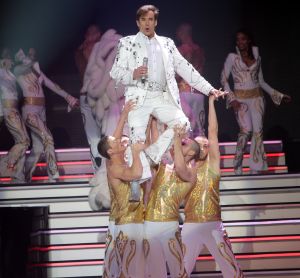 29-12-2007 SHOWBIZZ; CONCERT GERARD JOLING STOUT EN NIEUW 2007. Donderdag en Vrijdagavond was het weer een Joling feestje in de Ahoy. Dat Gerard zich thuis voelt in de Ahoy was direct te merken, de stemming zat er direct in na de eerste muzieknoten. De zanger was soms niet goed bij stem en moest het achtergrondkoortje het opvangen of Gerard liet het publiek zingen. Zijn vaak eigenzinnige grapjes waren meer dan eens op het randje en daar kan Dre Hazes van meepraten, zo vroeg Gerard aan Dre of ook alles lekker met hem meegroeide. Naast Dre Hazes trad ook Bonnie St.Clair op die opmerkelijk de tribunes deed schudden. Maaike en Tessa en Bearforce One deden hun eigen ding maar waren geen toevoeging tot de Joling Show. De knuffelberen van Bearforce One stonden volgens velen slecht te playbacken. De uitstraling van de show was niet echt Stout te noemen en had allemaal wat brutaler gemogen, ondanks de vele glitterpakken en veren jassen, daar maakt men de show niet Stout mee.De beloofde pikante en Stoute show heb ik niet gezien. Wel een echt Joling concert met een hoog Gaygehalte in het repertoire. Al met al was het een gezellig avondje uit voor de Joling fans al bestaan die voornamelijk uit Oma-s travestieten en studentes die in de pauze ook uit hun dak gingen toen de DJ een hit draaide van Frans Bauer.
foto: Albert den Iseger.