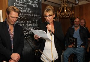 18-03-2012 SHOWBIZZ; SASKIA NOORT OVERHANDIGD EERSTE BOEK AAN JEUGDVRIEND RON MORET. Het boek met de titel SCHAAMSTREEK. Tekst is van de FLESSENPOST.
Schaamstreek, oesters en een koffie zet apparaat

Gistermiddag was het zo ver. De al eerder in het flesje aangekondigde presentatie van het boek de  Schaamstreek van schrijver Vincent Bakker bij restaurant Fabels vond plaats. De Bergense bestseller schrijfster Saskia Noort was uitgenodigd om het feestje op te leuken.
Ook de in deze contreien beroemde oesterkoning was aangekondigd, maar liet helaas verstek gaan. ondanks deze tegenslag vloeide de alcoholische drankjes rijkelijk. De Bergense kunstenaar Ron Moret staat centraal in het boek evenals de kunst10daagse 2011 en de Bergense kunst scene in zijn geheel. Saskia Noort hielt een warm, gloedvol en humoristisch betoog over het schrijfsel en Moret in het bijzonder. Het is slim en geniaal tegelijkertijd om daar eens een boekje over te schrijven, want ook landelijk wil men natuurlijk wel eens weten, wat er zich afspeelt in het sodom en gomora -bijgenaamd de Heerlijkheid- achter de duinen. 
Jammer is wel dat de schrijver zich blijkbaar niet realiseerde dat hij na de professionele presentatie van Noort er beter het zwijgen toe kan doen. En in plaats van wat onhoorbaar gemompel in een slecht afgestelde microfoon, eigenlijk alleen maar luidkeels hoeft te roepen, de Schaamstreek is bij alle Bergense boekhandels verkrijgbaar. maar alla de presentatie werd druk bezocht door een ieder die vindt dat hij tot de kunst scene behoord en natuurlijk ook die gene die hopen daar ooit toe kunnen behoren. En zelfs als dat laatste onmogelijk blijkt, dan is de iets te louwen kosteloos verkrijgbare bubbel toch altijd nog genoeg reden om aanwezig te zijn.
Als u nu denk, hoogste tijd om mezelf nu ook eindelijk eens op te dringen aan BB ers of BNers geen paniek, want u kunt op 21 maart a.s.  als ik het goed heb  met Saskia Noort aan tafel zitten samen met de schrijver Kluun bij ster restaurant Merlet. U kunt dan lunchen en twitteren voor het goede  iets met niet werkende spieren, naar ik me meen te herinneren  doel. Dus doe eens gek een prik met uw vorkje een sterretje weg. U kunt ook s-avond met  Michelin inspecteur  zanger Dries Roelvink aanschuiven, maar ik persoonlijk kies toch liever voor de lunch.
Verder Nog meer belangwekkend nieuws, want na lang wachten heeft niet alleen de Lamoraal een nieuwe handdoek automaat gekregen, maar na iets minder lang aandringen werd via een persbericht kenbaar gemaakt dat paviljoen  Uit de Kunst  een nieuw koffie zet apparaat heeft aangeschaft. Kortom wie beweert dat de horeca niet innovatief is heeft het mis. er gebeurt veel, heel veel
Op 31 maart a.s. daal bij Noord de afgang af, wandel een kwartier richting  de Kerf  en strijk neer bij een van de meest relaxte plekjes langs de Noordzeekust. Dan bestel ik een koffie  uit het nieuwe apparaat
  en ga eens lekker een uurtje  achet glas  over de Noordzee uit staren en over mijn zonden nadenken.., terwijl ik het net gedrukte en nu verkrijgbare boek 30 jaar Sissy-boy doorblader en denk wat een heerlijk schaamteloos dorp.
foto: Albert den Iseger
