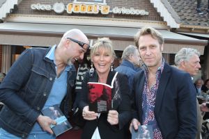 18-03-2012 SHOWBIZZ; SASKIA NOORT OVERHANDIGD EERSTE BOEK AAN JEUGDVRIEND RON MORET. Het boek met de titel SCHAAMSTREEK. Tekst is van de FLESSENPOST.
Schaamstreek, oesters en een koffie zet apparaat

Gistermiddag was het zo ver. De al eerder in het flesje aangekondigde presentatie van het boek de  Schaamstreek van schrijver Vincent Bakker bij restaurant Fabels vond plaats. De Bergense bestseller schrijfster Saskia Noort was uitgenodigd om het feestje op te leuken.
Ook de in deze contreien beroemde oesterkoning was aangekondigd, maar liet helaas verstek gaan. ondanks deze tegenslag vloeide de alcoholische drankjes rijkelijk. De Bergense kunstenaar Ron Moret staat centraal in het boek evenals de kunst10daagse 2011 en de Bergense kunst scene in zijn geheel. Saskia Noort hielt een warm, gloedvol en humoristisch betoog over het schrijfsel en Moret in het bijzonder. Het is slim en geniaal tegelijkertijd om daar eens een boekje over te schrijven, want ook landelijk wil men natuurlijk wel eens weten, wat er zich afspeelt in het sodom en gomora -bijgenaamd de Heerlijkheid- achter de duinen. 
Jammer is wel dat de schrijver zich blijkbaar niet realiseerde dat hij na de professionele presentatie van Noort er beter het zwijgen toe kan doen. En in plaats van wat onhoorbaar gemompel in een slecht afgestelde microfoon, eigenlijk alleen maar luidkeels hoeft te roepen, de Schaamstreek is bij alle Bergense boekhandels verkrijgbaar. maar alla de presentatie werd druk bezocht door een ieder die vindt dat hij tot de kunst scene behoord en natuurlijk ook die gene die hopen daar ooit toe kunnen behoren. En zelfs als dat laatste onmogelijk blijkt, dan is de iets te louwen kosteloos verkrijgbare bubbel toch altijd nog genoeg reden om aanwezig te zijn.
Als u nu denk, hoogste tijd om mezelf nu ook eindelijk eens op te dringen aan BB ers of BNers geen paniek, want u kunt op 21 maart a.s.  als ik het goed heb  met Saskia Noort aan tafel zitten samen met de schrijver Kluun bij ster restaurant Merlet. U kunt dan lunchen en twitteren voor het goede  iets met niet werkende spieren, naar ik me meen te herinneren  doel. Dus doe eens gek een prik met uw vorkje een sterretje weg. U kunt ook s-avond met  Michelin inspecteur  zanger Dries Roelvink aanschuiven, maar ik persoonlijk kies toch liever voor de lunch.
Verder Nog meer belangwekkend nieuws, want na lang wachten heeft niet alleen de Lamoraal een nieuwe handdoek automaat gekregen, maar na iets minder lang aandringen werd via een persbericht kenbaar gemaakt dat paviljoen  Uit de Kunst  een nieuw koffie zet apparaat heeft aangeschaft. Kortom wie beweert dat de horeca niet innovatief is heeft het mis. er gebeurt veel, heel veel
Op 31 maart a.s. daal bij Noord de afgang af, wandel een kwartier richting  de Kerf  en strijk neer bij een van de meest relaxte plekjes langs de Noordzeekust. Dan bestel ik een koffie  uit het nieuwe apparaat
  en ga eens lekker een uurtje  achet glas  over de Noordzee uit staren en over mijn zonden nadenken.., terwijl ik het net gedrukte en nu verkrijgbare boek 30 jaar Sissy-boy doorblader en denk wat een heerlijk schaamteloos dorp.
foto: Albert den Iseger
