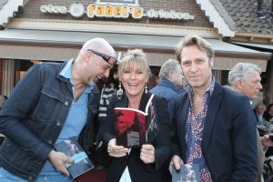 18-03-2012 SHOWBIZZ; SASKIA NOORT OVERHANDIGD EERSTE BOEK AAN JEUGDVRIEND RON MORET. Het boek met de titel SCHAAMSTREEK. Tekst is van de FLESSENPOST.
Schaamstreek, oesters en een koffie zet apparaat

Gistermiddag was het zo ver. De al eerder in het flesje aangekondigde presentatie van het boek de  Schaamstreek van schrijver Vincent Bakker bij restaurant Fabels vond plaats. De Bergense bestseller schrijfster Saskia Noort was uitgenodigd om het feestje op te leuken.
Ook de in deze contreien beroemde oesterkoning was aangekondigd, maar liet helaas verstek gaan. ondanks deze tegenslag vloeide de alcoholische drankjes rijkelijk. De Bergense kunstenaar Ron Moret staat centraal in het boek evenals de kunst10daagse 2011 en de Bergense kunst scene in zijn geheel. Saskia Noort hielt een warm, gloedvol en humoristisch betoog over het schrijfsel en Moret in het bijzonder. Het is slim en geniaal tegelijkertijd om daar eens een boekje over te schrijven, want ook landelijk wil men natuurlijk wel eens weten, wat er zich afspeelt in het sodom en gomora -bijgenaamd de Heerlijkheid- achter de duinen. 
Jammer is wel dat de schrijver zich blijkbaar niet realiseerde dat hij na de professionele presentatie van Noort er beter het zwijgen toe kan doen. En in plaats van wat onhoorbaar gemompel in een slecht afgestelde microfoon, eigenlijk alleen maar luidkeels hoeft te roepen, de Schaamstreek is bij alle Bergense boekhandels verkrijgbaar. maar alla de presentatie werd druk bezocht door een ieder die vindt dat hij tot de kunst scene behoord en natuurlijk ook die gene die hopen daar ooit toe kunnen behoren. En zelfs als dat laatste onmogelijk blijkt, dan is de iets te louwen kosteloos verkrijgbare bubbel toch altijd nog genoeg reden om aanwezig te zijn.
Als u nu denk, hoogste tijd om mezelf nu ook eindelijk eens op te dringen aan BB ers of BNers geen paniek, want u kunt op 21 maart a.s.  als ik het goed heb  met Saskia Noort aan tafel zitten samen met de schrijver Kluun bij ster restaurant Merlet. U kunt dan lunchen en twitteren voor het goede  iets met niet werkende spieren, naar ik me meen te herinneren  doel. Dus doe eens gek een prik met uw vorkje een sterretje weg. U kunt ook s-avond met  Michelin inspecteur  zanger Dries Roelvink aanschuiven, maar ik persoonlijk kies toch liever voor de lunch.
Verder Nog meer belangwekkend nieuws, want na lang wachten heeft niet alleen de Lamoraal een nieuwe handdoek automaat gekregen, maar na iets minder lang aandringen werd via een persbericht kenbaar gemaakt dat paviljoen  Uit de Kunst  een nieuw koffie zet apparaat heeft aangeschaft. Kortom wie beweert dat de horeca niet innovatief is heeft het mis. er gebeurt veel, heel veel
Op 31 maart a.s. daal bij Noord de afgang af, wandel een kwartier richting  de Kerf  en strijk neer bij een van de meest relaxte plekjes langs de Noordzeekust. Dan bestel ik een koffie  uit het nieuwe apparaat
  en ga eens lekker een uurtje  achet glas  over de Noordzee uit staren en over mijn zonden nadenken.., terwijl ik het net gedrukte en nu verkrijgbare boek 30 jaar Sissy-boy doorblader en denk wat een heerlijk schaamteloos dorp.
foto: Albert den Iseger
