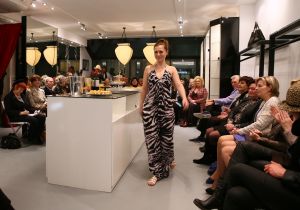 31-03-2013 SHOWBIZZ; SHEILA DE VRIES GEEFT EXCLUSIEVE AVONDSHOW. AMSTERDAM - Het is akelig koud de hele week. Een snijdende wind, constateerde fashiondesigner Sheila De Vries die een exclusieve avondshow geeft voor haar klanten in haar winkel Sheila & Gideon Collections in de Cornelis Schuytstraat. Maar ondanks het ijskoude weer presenteren wij vanavond toch veel lange luchtige zomerjurken met een lage rug. Sheila De Vries werd onder meer bekend door de prachtige couture die zij ontwerpt voor Koningin Beatrix. Iedereen wacht met spanning op De Jurk van 30 april. Maar vanavond wordt haar show gepresenteerd door ... de actrices van Purper.
Zij laten in haar winkel in de hoofdstad haar nieuwe collectie zien. Met veel lange jurken en kaftans voor iedere maat en figuur. Van slankmakende voile en kantachtige materialen. Sheila reist de hele wereld af voor deze unieke stoffen waarvan zij zeer verschillende creaties maakt. Deze keer adviseert zij haar klanten voor de zomer altijd iets van zwart en wit in de kast te hebben. En dat mag ook best in een dessin zijn uitgevoerd.
Sheila maakt prachtige feelgood-jurken die iedere vrouw zowel op een gala als op een avond thuis fasntastisch staan. Jasjes met een meesterlijk dessin, bijzondere tassen, schoenen en sieraden naar eigen ontwerp. En Gideon toont markante jacks voor de moderne man. 
Alle actrices van Purper hebben hun eigen onnavolgbare manier om de creaties van Sheila aan de klanten te tonen. De markante verschijning van Gerrie Van der Klei is onvergetelijk als zij tijdens haar ronde in een lange krijtwitte en rechte jurk van opengewerkt materiaal vol waardigheid met een grote donkere bril op snel een slokje uit een glas wijn gapt. Zoiets zul je een echte mannequin nooit zien doen. Celine Purcell met haar grappige uitstraling is eenvoudig zichzelf.
Ook de blonde Mylou Frencken maakt tijdens deze show wat vrolijke danspassen die herinneren aan de Zumba van de sportschool. Enkele van de klanten van Sheila vertellen mij tijdens de afterparty deze show zo waarderen omdat hier nu eens dames met echte rondingen te zien zijn die ieder hun eigen stijl hebben... Dat klopt want de mysterieuze gratie van professionele mannequins is echt een vak apart. Toch weet Sheila s muze Anouk Van Nes als getraind danseres in een lange zwarte galajurk deze stijl met haar bijzondere flair goed te presenteren.
Het publiek houdt af en toe de adem in bij deze bijzondere Purper-presentatie. Maar hoe verrassend is dit theaterseizoen waar in plaats van vier heren in rokkostuum nu eens een groep van vier vrouwen in rok op de buhne als Purper optreedt. Vier dames die van wanten weten! De Purper Ladies zijn Gerrie Van der Klei, Anouk Van Nes, Celine Purcell en Mylou Frencken.
Vier vakvrouwen ook die hun sporen in het theater ruimschoots hebben verdiend en garant staan voor topkwaliteit, passend bij de Purper traditie. Een traditie die zich in het komend seizoen zal vernieuwen en verdiepen. Vrouwen van verschillende leeftijd en achtergrond die het publiek een avondlang zinnig entertainen. Vrouwen met lef, gein en geweldige stemmen. Het moet een Purper op haar best worden. Uniek. Als genre op zich, niet te imiteren.
Thema: Hoe staan vrouwen van verschillende leeftijden vandaag de dag in het leven? Een onderwerp dat met een gezonde dosis zelfspot tot een hilarische theateravond zal leiden. 
Fasten your seatbelts: de Purper Ladies komen eraan! Het wordt een heerlijk avondje uit!
foto: Albert den Iseger.