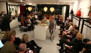31-03-2013 SHOWBIZZ; SHEILA DE VRIES GEEFT EXCLUSIEVE AVONDSHOW. AMSTERDAM - Het is akelig koud de hele week. Een snijdende wind, constateerde fashiondesigner Sheila De Vries die een exclusieve avondshow geeft voor haar klanten in haar winkel Sheila & Gideon Collections in de Cornelis Schuytstraat. Maar ondanks het ijskoude weer presenteren wij vanavond toch veel lange luchtige zomerjurken met een lage rug. Sheila De Vries werd onder meer bekend door de prachtige couture die zij ontwerpt voor Koningin Beatrix. Iedereen wacht met spanning op De Jurk van 30 april. Maar vanavond wordt haar show gepresenteerd door ... de actrices van Purper.
Zij laten in haar winkel in de hoofdstad haar nieuwe collectie zien. Met veel lange jurken en kaftans voor iedere maat en figuur. Van slankmakende voile en kantachtige materialen. Sheila reist de hele wereld af voor deze unieke stoffen waarvan zij zeer verschillende creaties maakt. Deze keer adviseert zij haar klanten voor de zomer altijd iets van zwart en wit in de kast te hebben. En dat mag ook best in een dessin zijn uitgevoerd.
Sheila maakt prachtige feelgood-jurken die iedere vrouw zowel op een gala als op een avond thuis fasntastisch staan. Jasjes met een meesterlijk dessin, bijzondere tassen, schoenen en sieraden naar eigen ontwerp. En Gideon toont markante jacks voor de moderne man. 
Alle actrices van Purper hebben hun eigen onnavolgbare manier om de creaties van Sheila aan de klanten te tonen. De markante verschijning van Gerrie Van der Klei is onvergetelijk als zij tijdens haar ronde in een lange krijtwitte en rechte jurk van opengewerkt materiaal vol waardigheid met een grote donkere bril op snel een slokje uit een glas wijn gapt. Zoiets zul je een echte mannequin nooit zien doen. Celine Purcell met haar grappige uitstraling is eenvoudig zichzelf.
Ook de blonde Mylou Frencken maakt tijdens deze show wat vrolijke danspassen die herinneren aan de Zumba van de sportschool. Enkele van de klanten van Sheila vertellen mij tijdens de afterparty deze show zo waarderen omdat hier nu eens dames met echte rondingen te zien zijn die ieder hun eigen stijl hebben... Dat klopt want de mysterieuze gratie van professionele mannequins is echt een vak apart. Toch weet Sheila s muze Anouk Van Nes als getraind danseres in een lange zwarte galajurk deze stijl met haar bijzondere flair goed te presenteren.
Het publiek houdt af en toe de adem in bij deze bijzondere Purper-presentatie. Maar hoe verrassend is dit theaterseizoen waar in plaats van vier heren in rokkostuum nu eens een groep van vier vrouwen in rok op de buhne als Purper optreedt. Vier dames die van wanten weten! De Purper Ladies zijn Gerrie Van der Klei, Anouk Van Nes, Celine Purcell en Mylou Frencken.
Vier vakvrouwen ook die hun sporen in het theater ruimschoots hebben verdiend en garant staan voor topkwaliteit, passend bij de Purper traditie. Een traditie die zich in het komend seizoen zal vernieuwen en verdiepen. Vrouwen van verschillende leeftijd en achtergrond die het publiek een avondlang zinnig entertainen. Vrouwen met lef, gein en geweldige stemmen. Het moet een Purper op haar best worden. Uniek. Als genre op zich, niet te imiteren.
Thema: Hoe staan vrouwen van verschillende leeftijden vandaag de dag in het leven? Een onderwerp dat met een gezonde dosis zelfspot tot een hilarische theateravond zal leiden. 
Fasten your seatbelts: de Purper Ladies komen eraan! Het wordt een heerlijk avondje uit!
foto: Albert den Iseger.